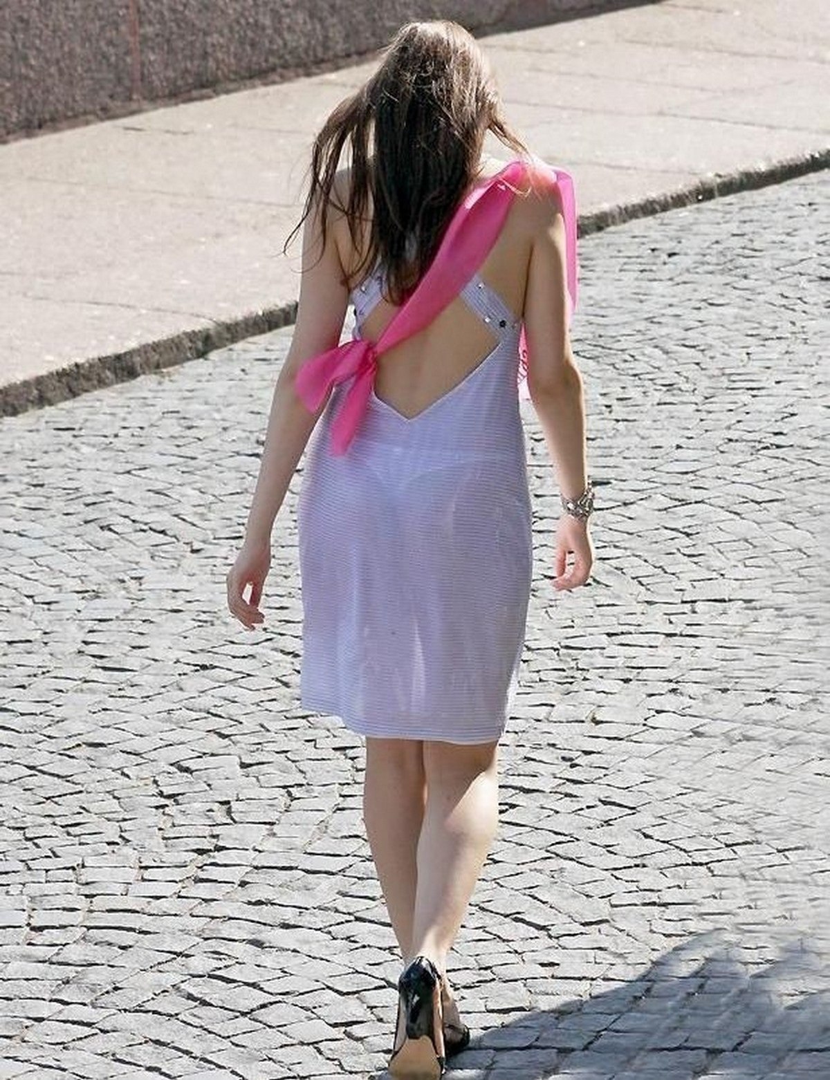 Привлекательная брюнетка модель в прозрачном платье гуляет по улице в лучах солнца | Премиум Фото